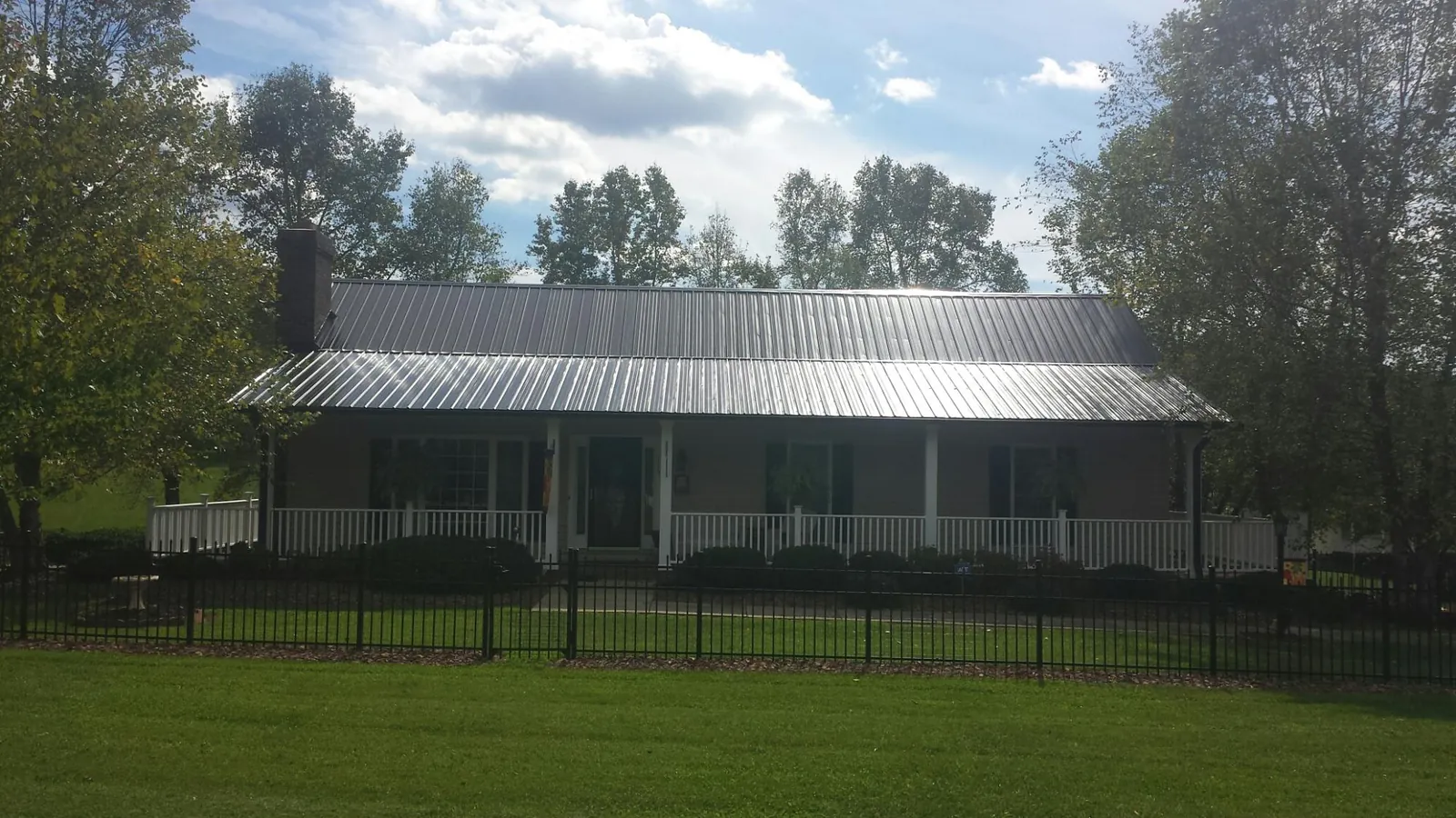 Gray metal roof on a brick ranch with a full width front porch — Gutter Guard Installation work by our crew in Clarksburg